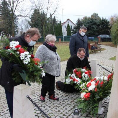 Wójt Tadeusz Kielan, proboszcz Paweł Kajl, sołtys Alina Majewska i przewodniczący Rady Gminy Norbert Grabowski składają kwiaty pod tablicą pamięci Józefa Piłsudskiego.