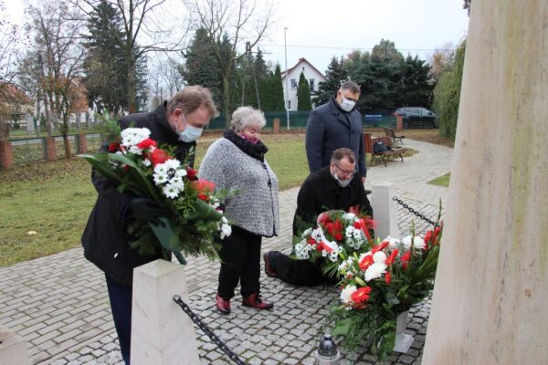 Wójt Tadeusz Kielan, proboszcz Paweł Kajl, sołtys Alina Majewska i przewodniczący Rady Gminy Norbert Grabowski składają kwiaty pod tablicą pamięci Józefa Piłsudskiego.