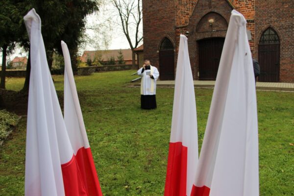 Kisądz Tadeusz Żurek na tle flag