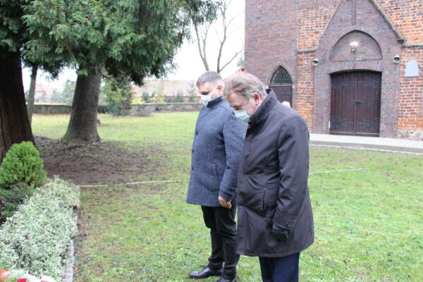 Wójt i przewodniczący składają kwiaty.