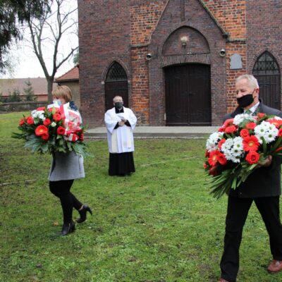 Sołtys Stanisław Ryniec i Agnieszka Szumlańska składają kwiaty.