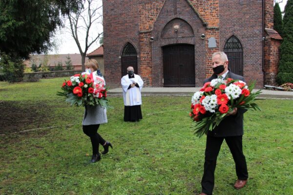 Sołtys Stanisław Ryniec i Agnieszka Szumlańska składają kwiaty.