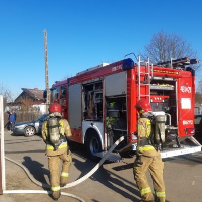 Strażacy na tle wozu gaśnieczego.