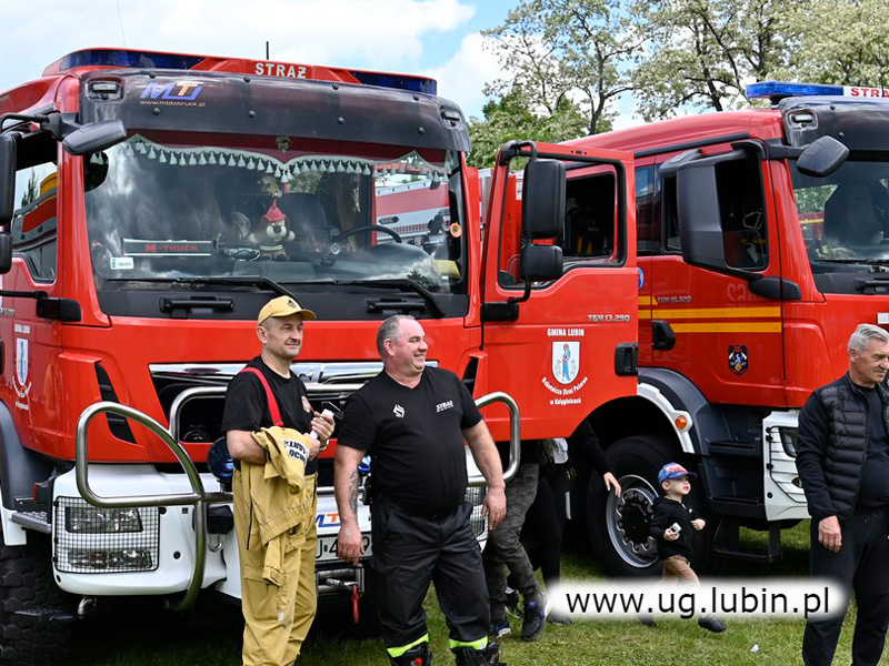 Powiatowy Festyn Strażacki gminy Lubin. Strażacy na tle wozu gaśniczego.